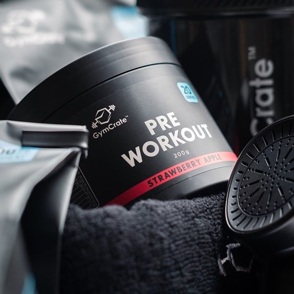 GymCrate Strawberry Apple PreWorkout next to a gym towel, protein shaker, whey protein
